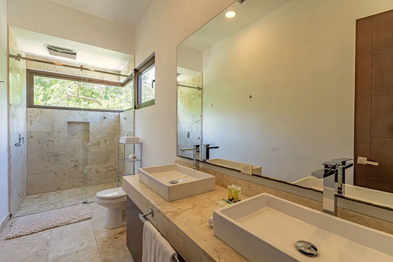 Baño con doble lavabo y regadera de piedra