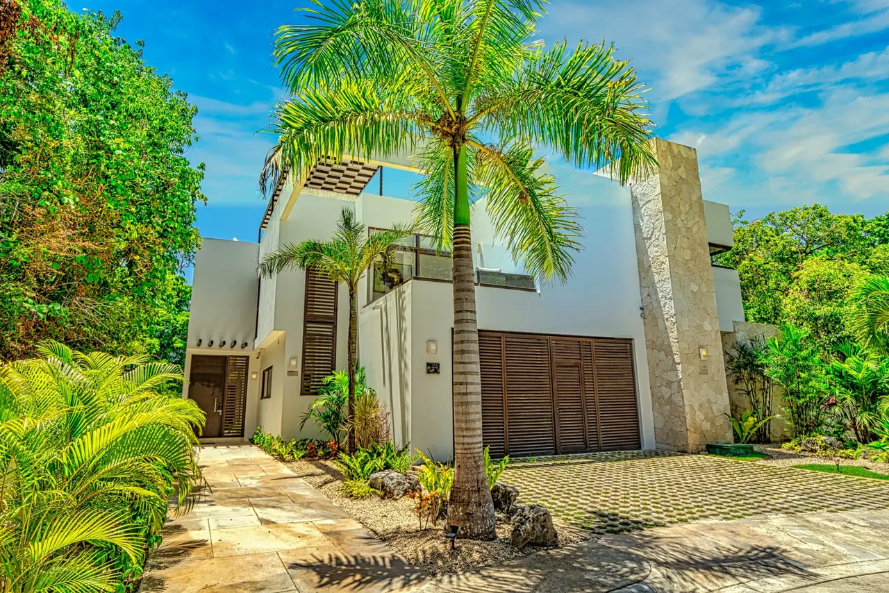 Fachada de la casa con palmeras y portón de madera
